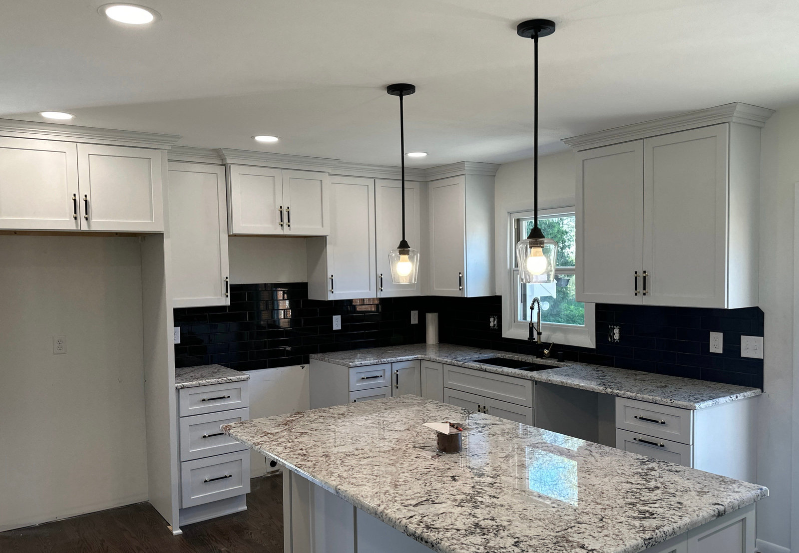 White cabinetry, a stone island, and pendant lighting