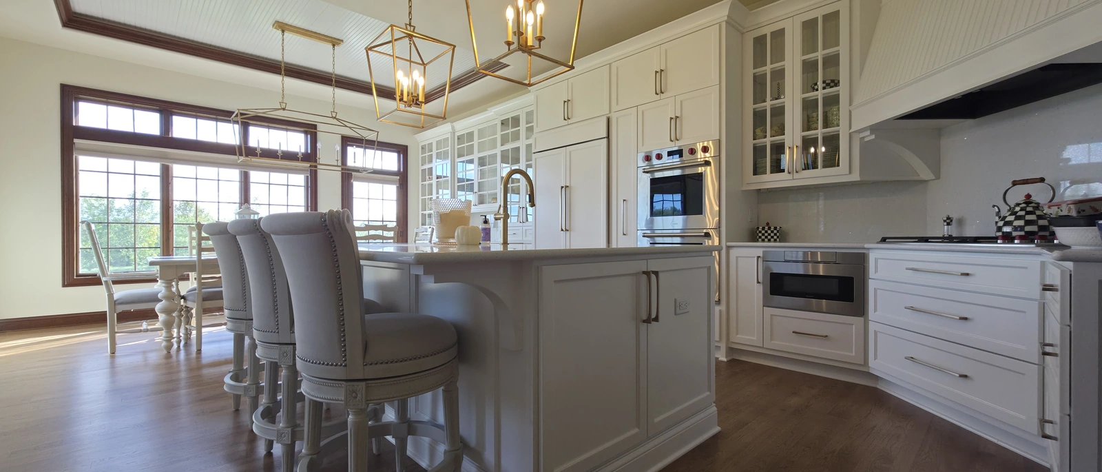 After remodeling: white cabinetry, an island, brass pendant lighting, and integrated appliances in the kitchen