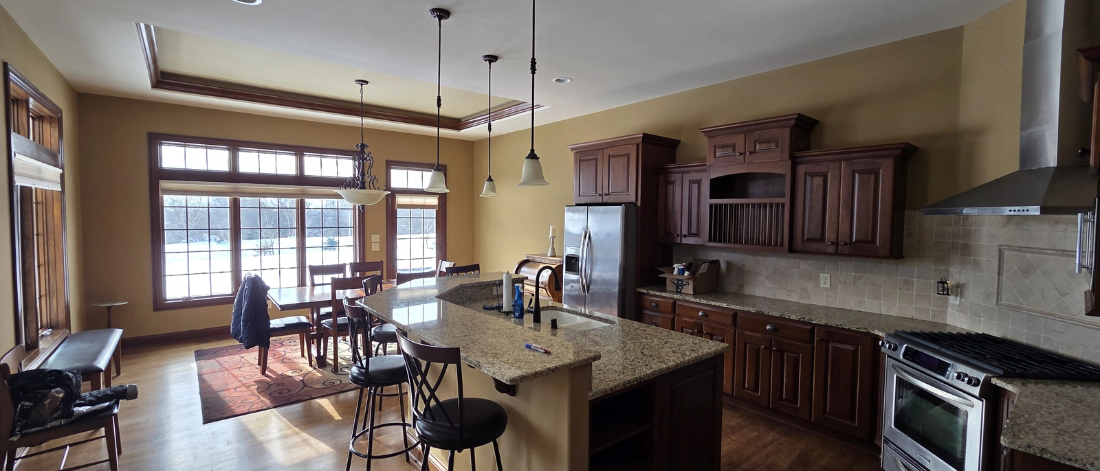 Before remodeling: dark wood cabinets, a raised granite island, and hanging lights in the same kitchen