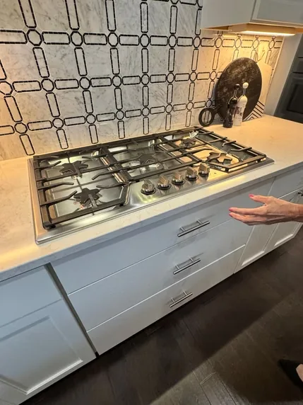 Stainless steel gas cooktop fitted into a white kitchen countertop