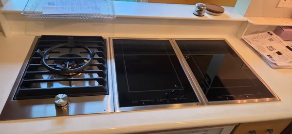 A gas cooking module beside a dark glass cooktop.