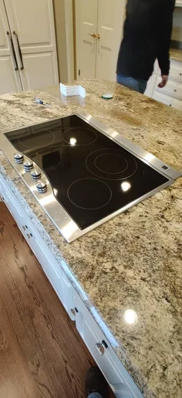 Black glass cooktop fitted into a stone countertop