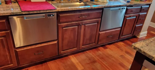 Stainless steel dish drawers set into warm wood cabinetry.