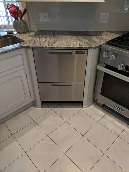 A stainless steel dishwasher set within a white kitchen.