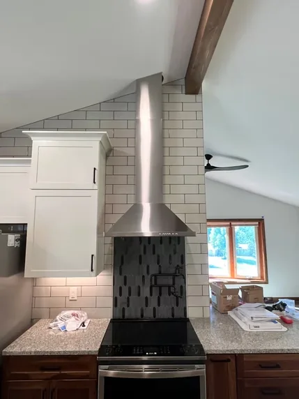 A stainless steel chimney hood beneath a sloped ceiling.