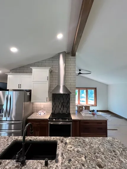 Stainless steel chimney hood above a range in a kitchen with a sloped ceiling
