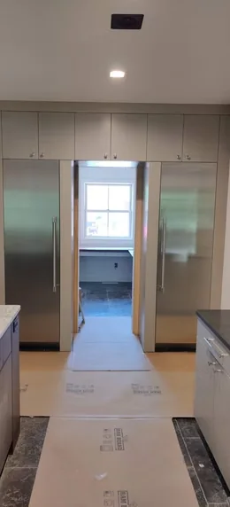 Panel-front refrigeration within tall white kitchen cabinetry