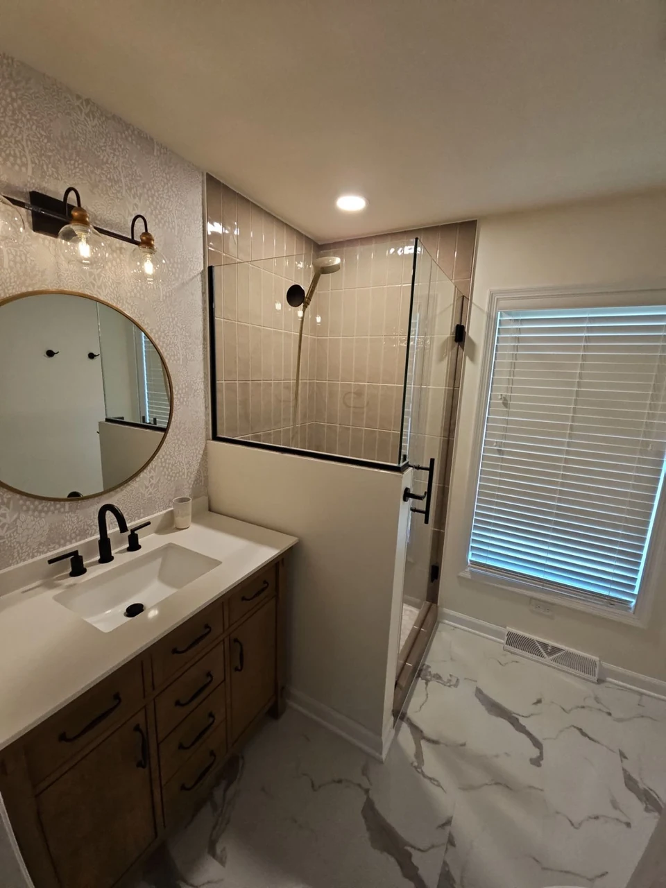 Wood vanity and glass shower in a completed bathroom