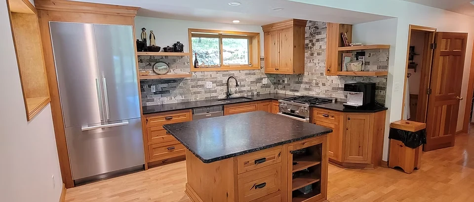 Warm wood cabinetry, dark countertops, and an island in the Lodi Lake House remodel